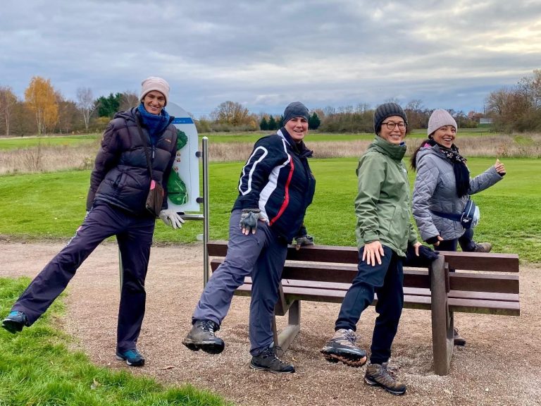 Gruppe von neun Personen in der Natur, umgeben von Bäumen, mit einem Hund in der Mitte.